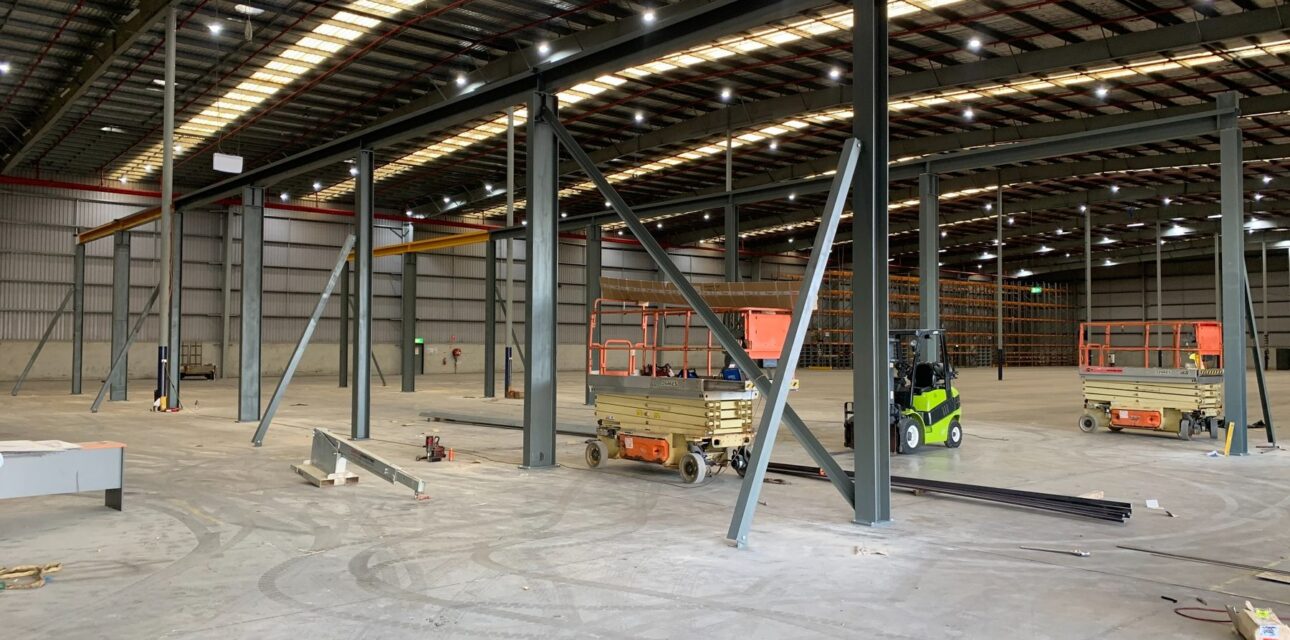 Crane supporting steel structure and runway beams during warehouse installation