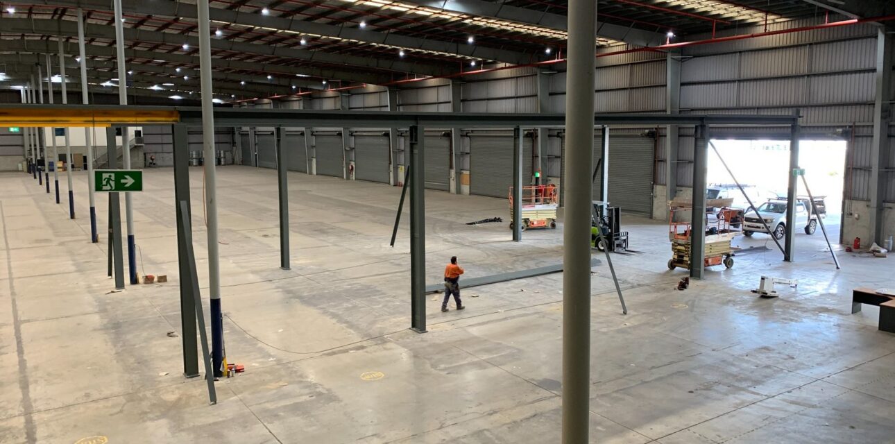 Industrial crane runway system being installed inside a large warehouse facility