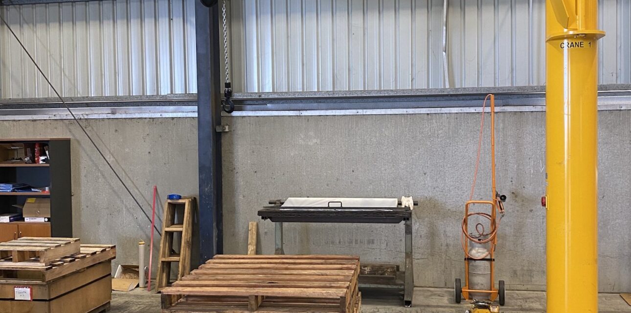 1‑tonne free‑standing jib crane with electric hoist inside workshop.