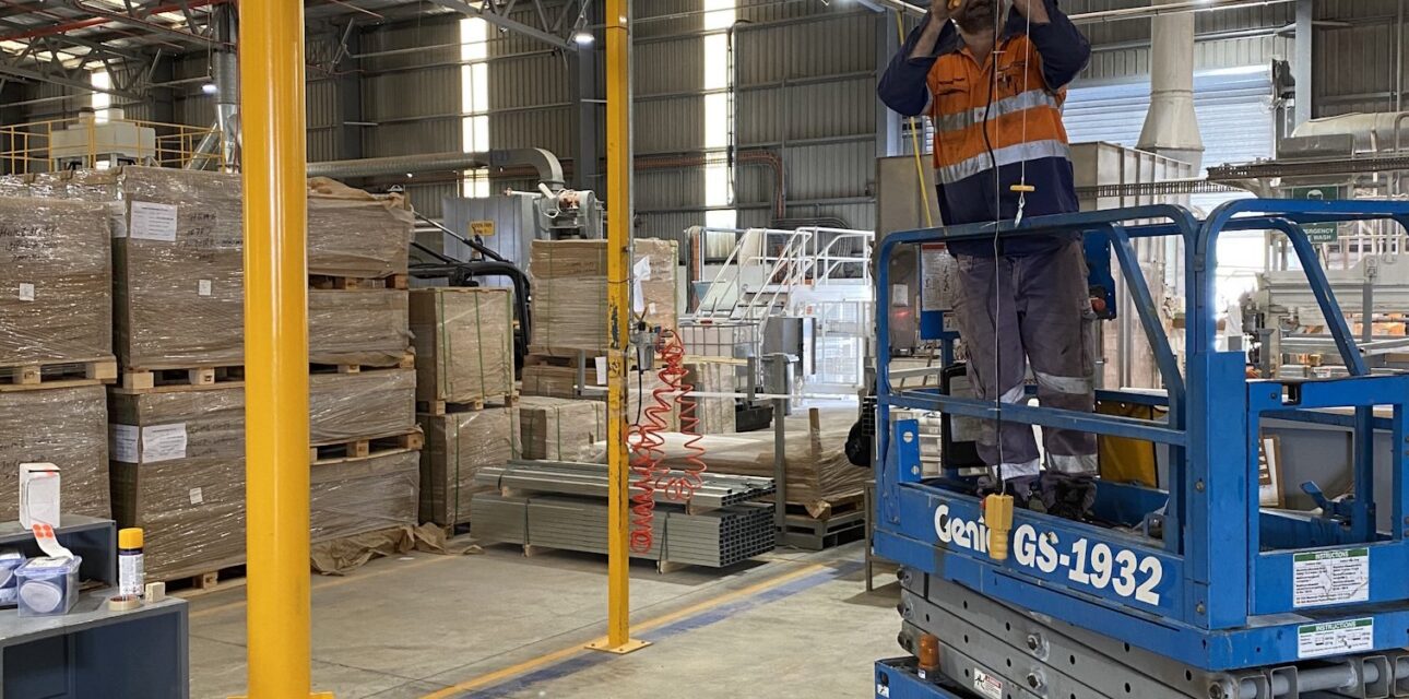 Free‑standing jib crane installation with technician performing maintenance.