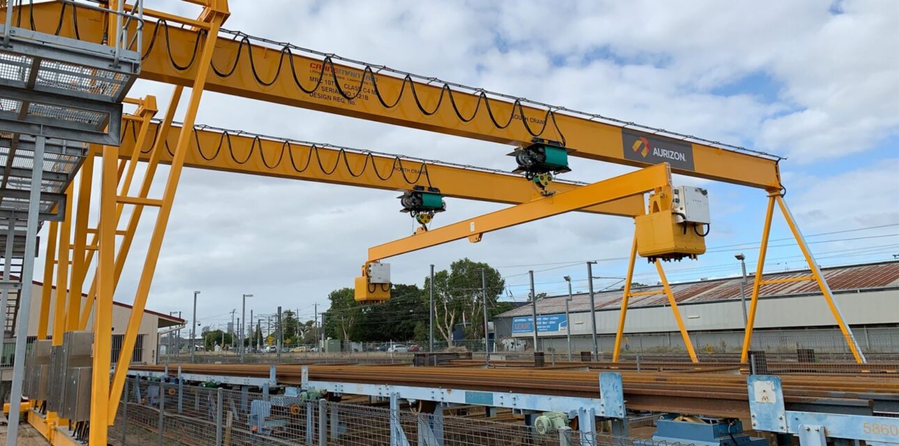 Dual portal cranes with wire rope hoists over a rail material handling area