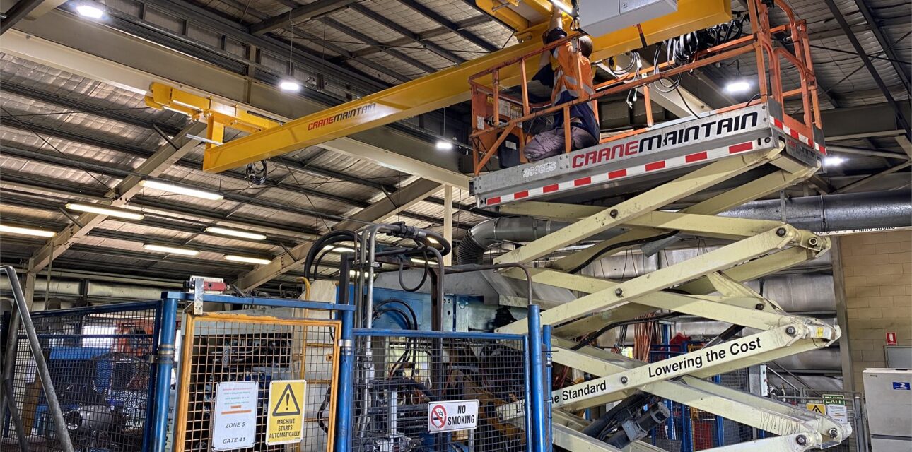 Underslung overhead crane installation with technicians working from a scissor lift