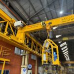 Overhead crane with custom lifting attachment and control cabin.