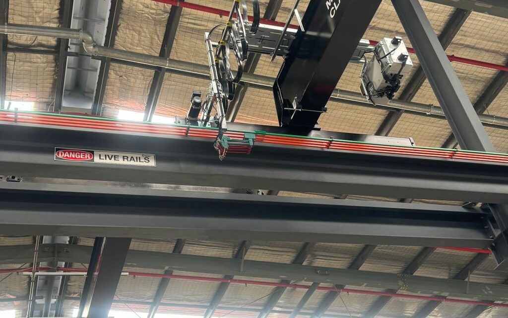 Close‑up of overhead crane showing festoon cable system and live rails.