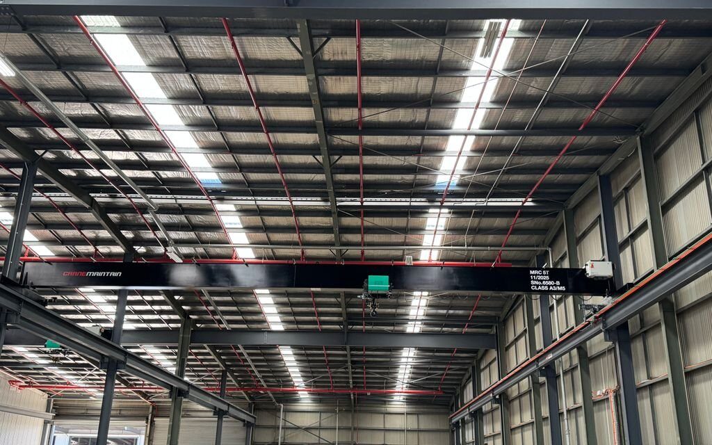 Single girder overhead crane spanning industrial workshop.