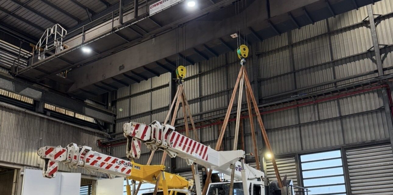 Heavy‑duty overhead crane performing load test lifting mobile cranes.