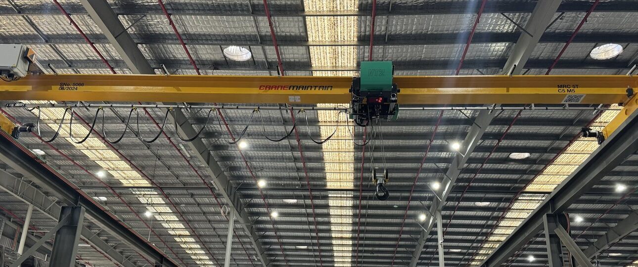 Yellow overhead crane with electric hoist and festoon system.